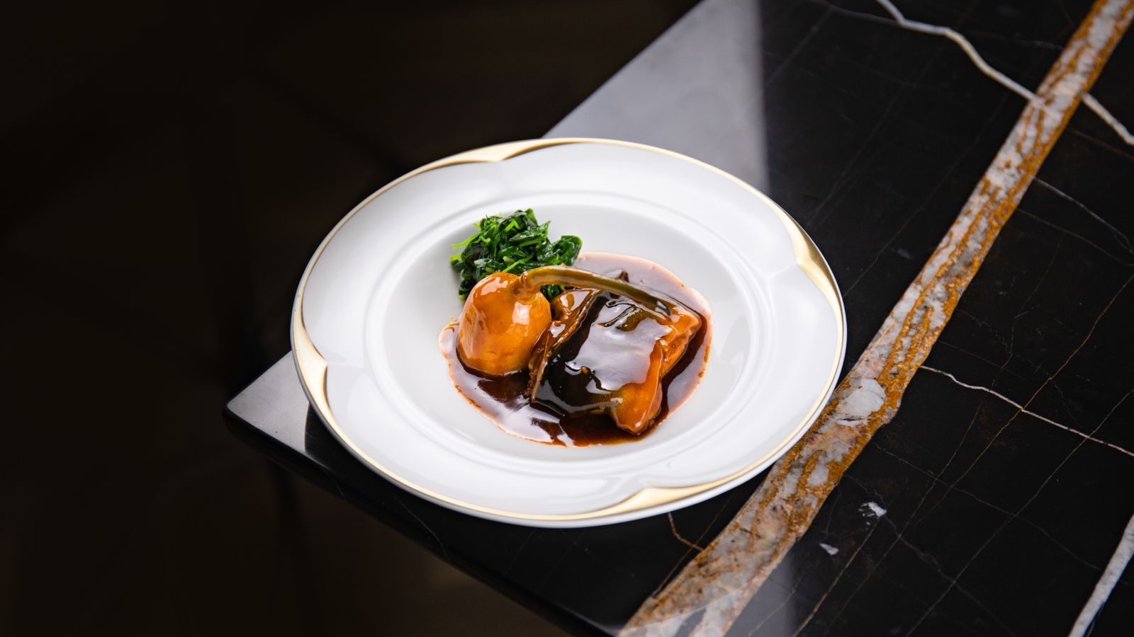 An elegant plated dish on a dark marble table, the kind of dining the best all inclusive cruises include
