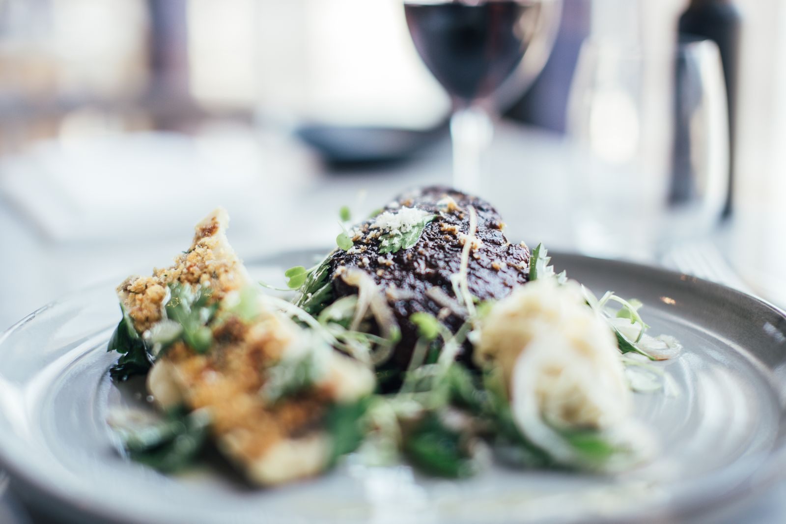 A plated steak and vegetables with a glass of red wine, dining that adds to the total cost of a cruise